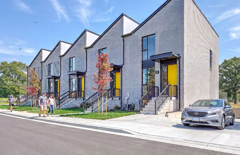 Site photo of the built Park Townhomes at Unity Square, with yellow entrance doors facing the street.